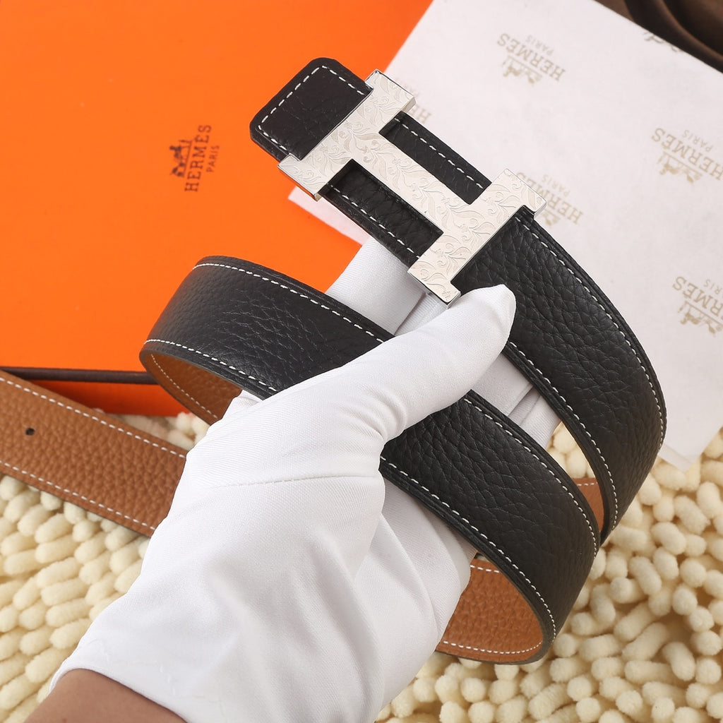 Black leather belt with gold-tone buckle and tan underside, stitched trim and keeper tab