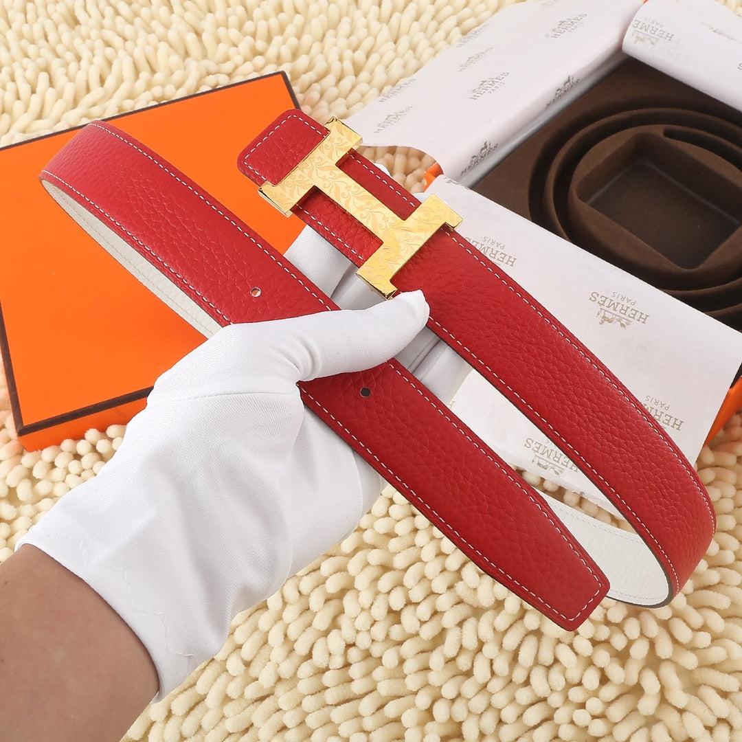 Hermes leather belt laid flat, red strap with white edge and silver-tone H buckle