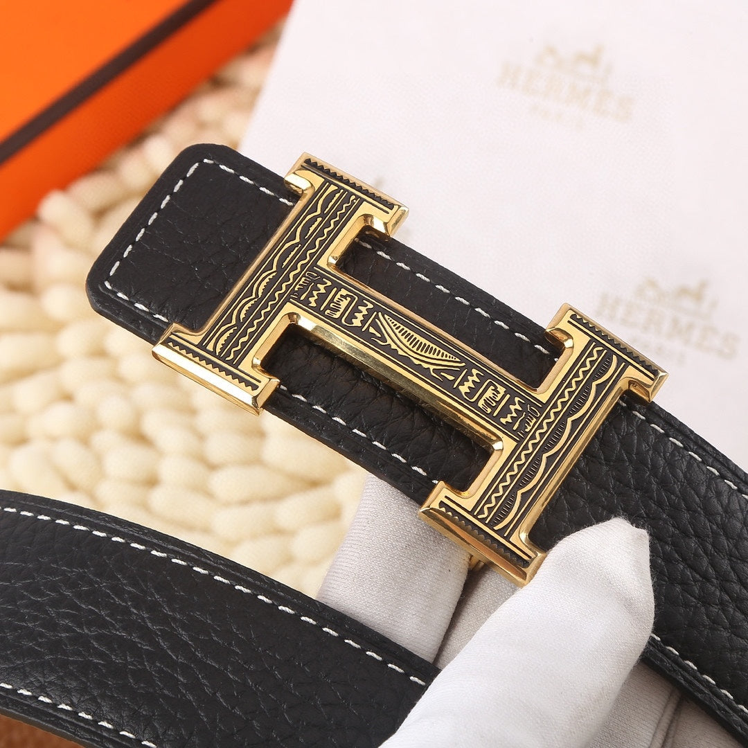 Black leather belt close-up of gold buckle with engraved frame