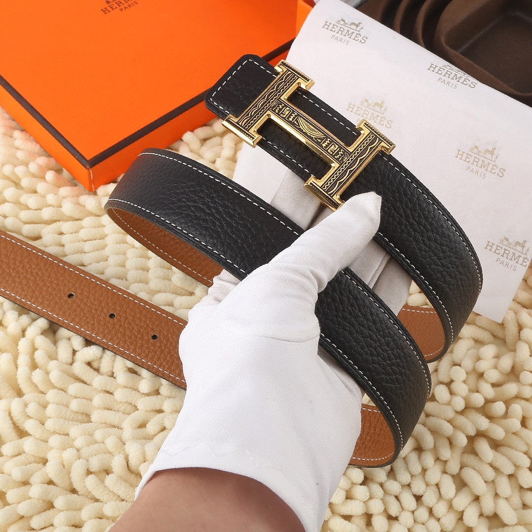 Black leather belt with brown underside and gold buckle, held for display