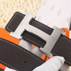 Dark leather belt closeup of gold-tone buckle hardware with white contrast stitching.