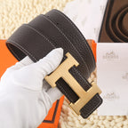 Dark leather belt with gold-tone H buckle and white contrast stitching, angled view.