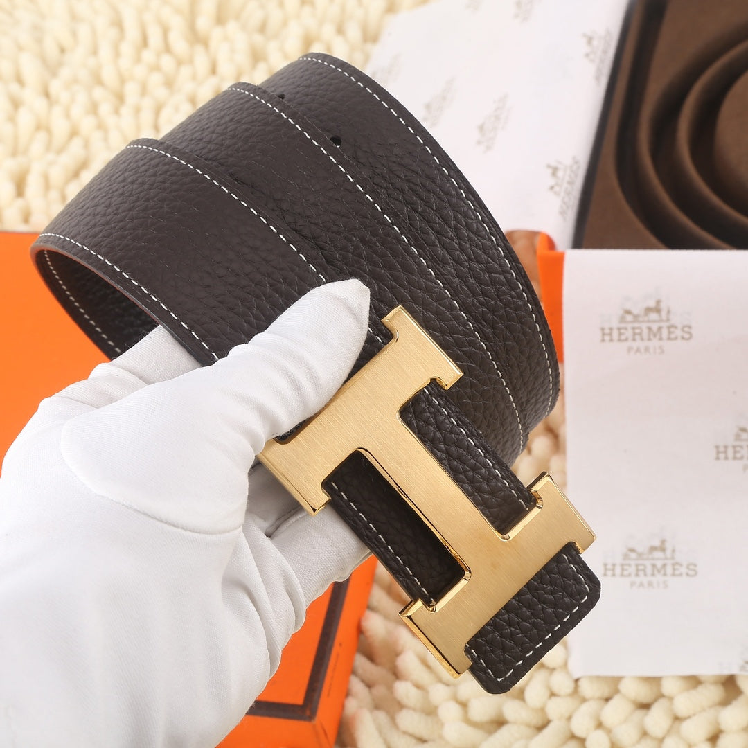 Dark leather belt with gold-tone H buckle and white contrast stitching, angled view.