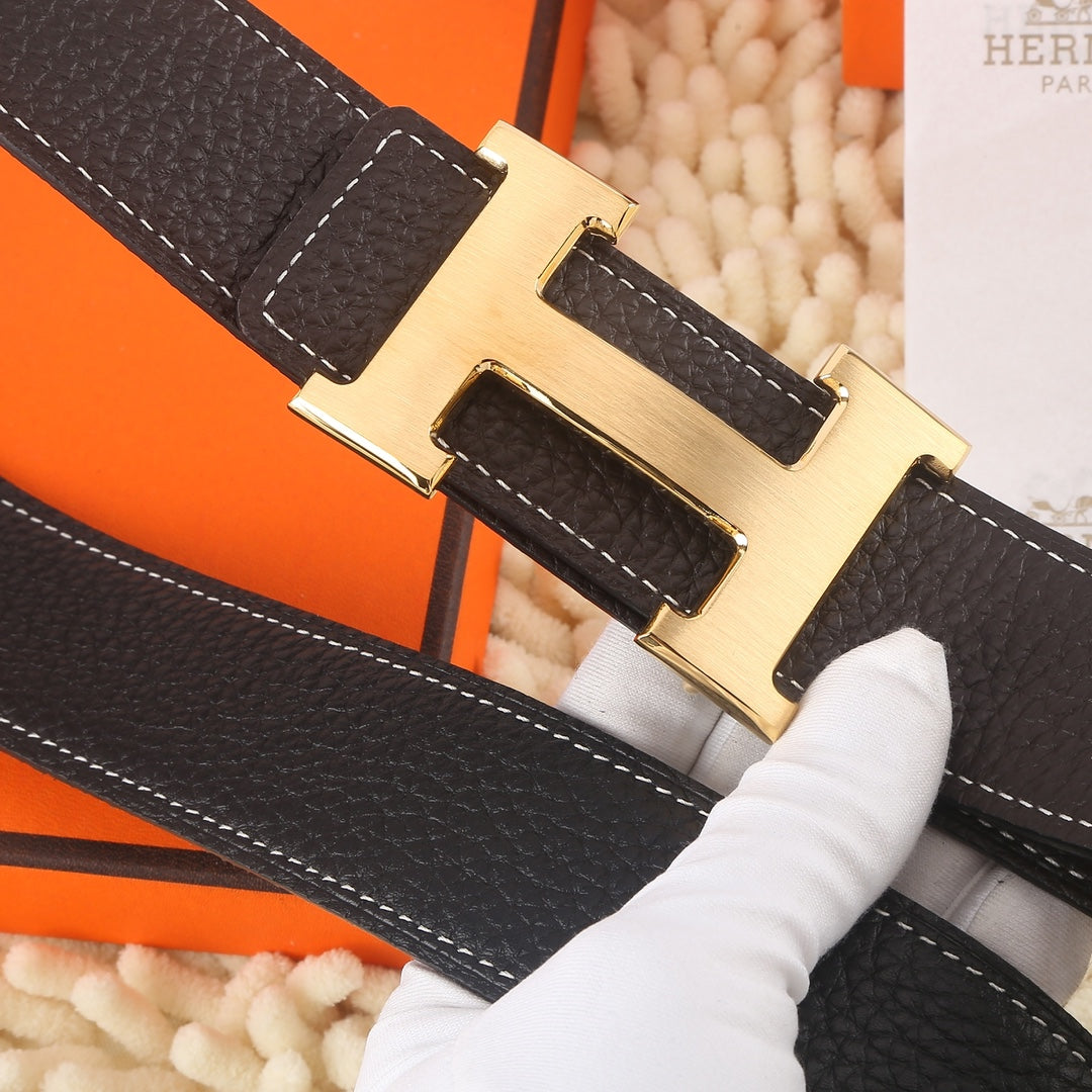 Dark leather belt closeup with gold-tone buckle and white contrast edge stitching.