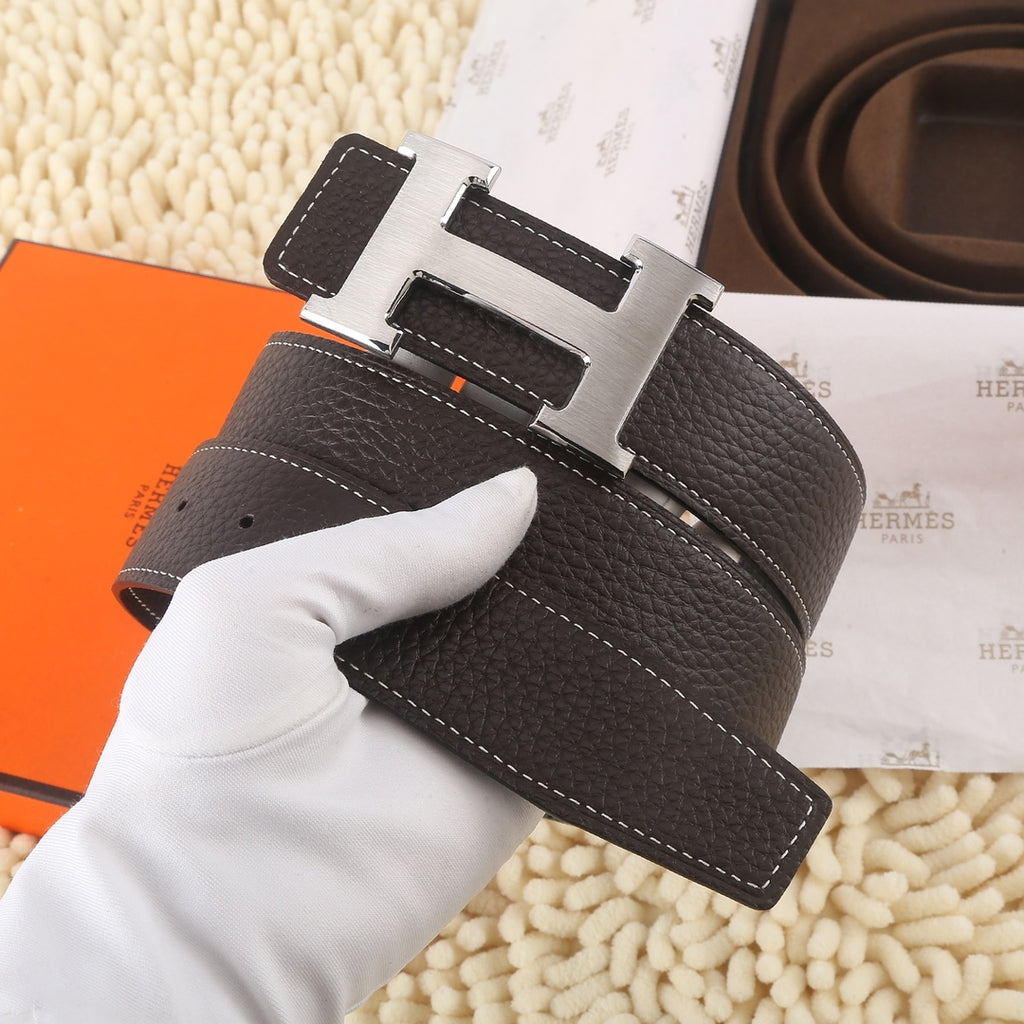 Dark leather belt with gold-tone buckle and white contrast stitching, front closeup.