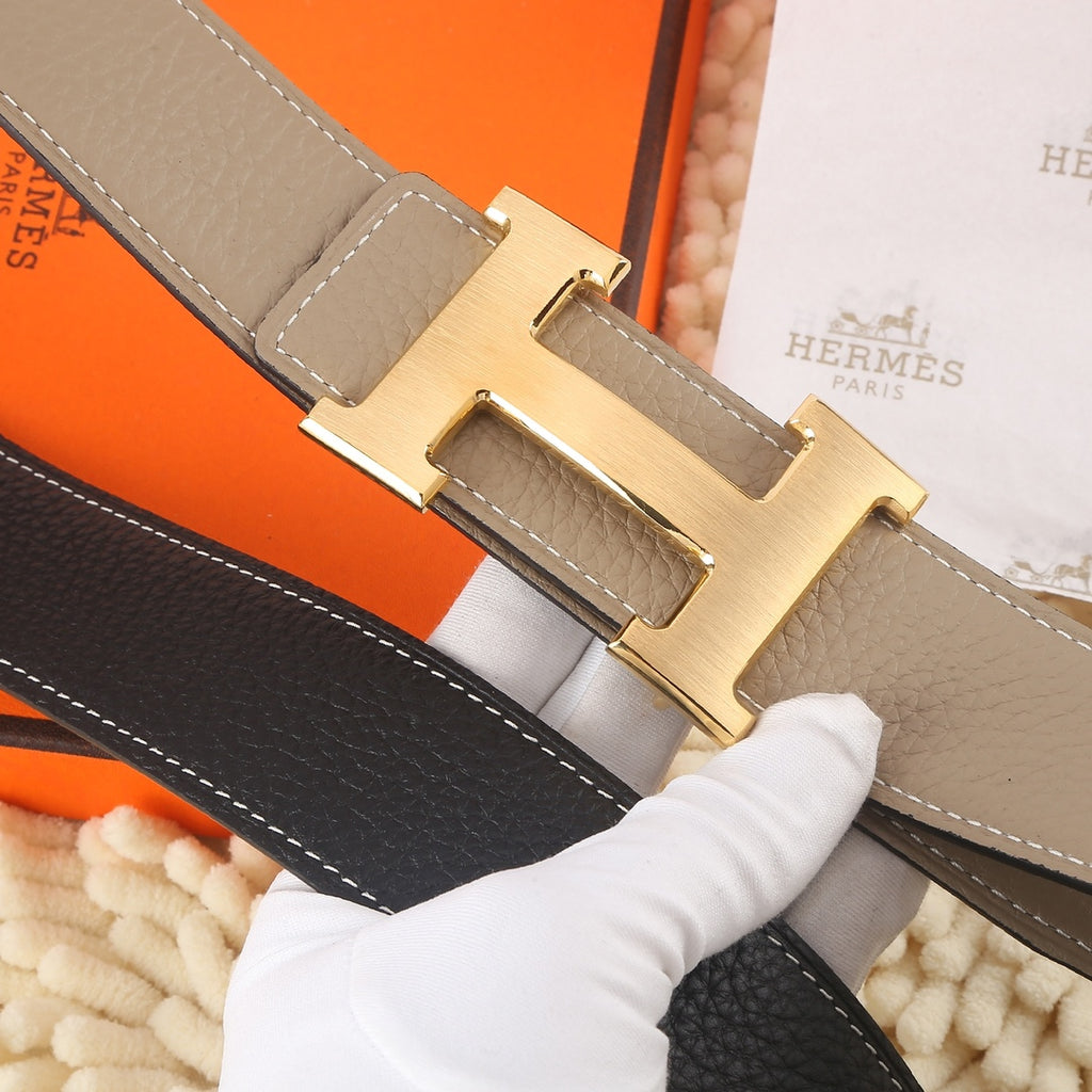 Hermes belt buckle detail: gold H clasp on taupe leather with black lining.