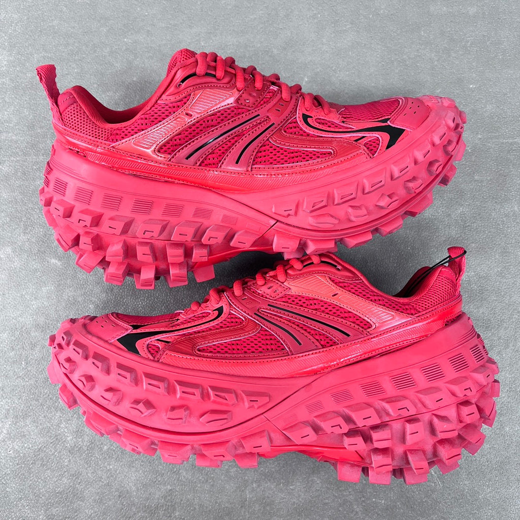 Pair of pink athletic shoes with rugged tread sole and lace-up front, side view