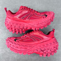Pair of pink athletic shoes with rugged tread sole and lace-up front, side view