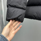 Dark puffer jacket hem with elastic cuff; close-up held by hand