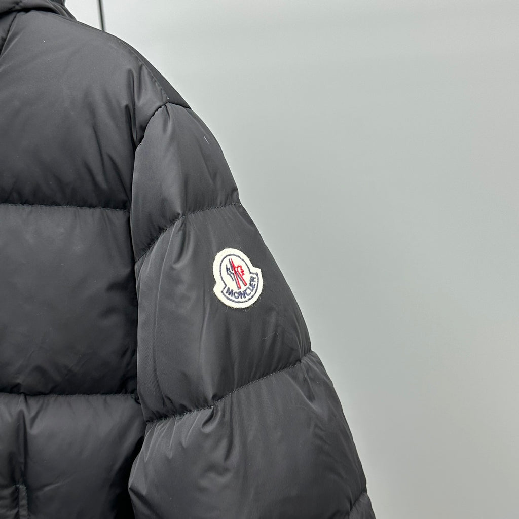 Dark puffer jacket sleeve with round logo patch and stitched paneling