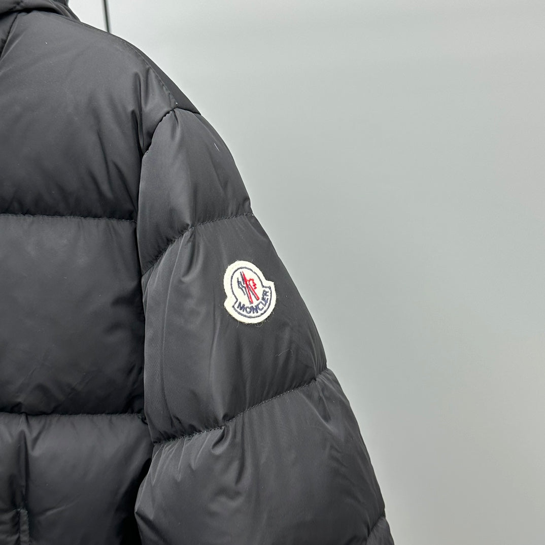 Dark puffer jacket sleeve with round logo patch and stitched paneling