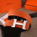 Leather belt with orange strap and silver H buckle over black keeper