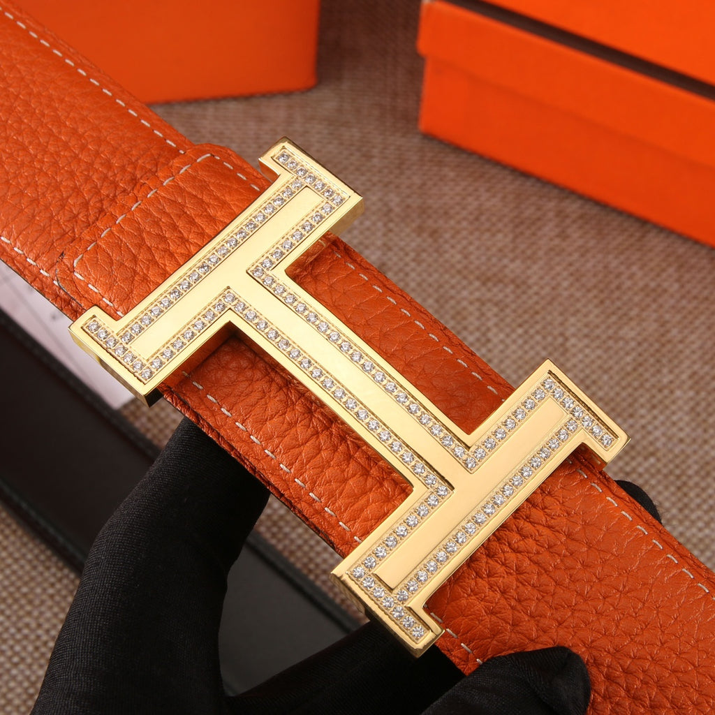 Leather belt detail: orange strap with silver H buckle and sparkling trim