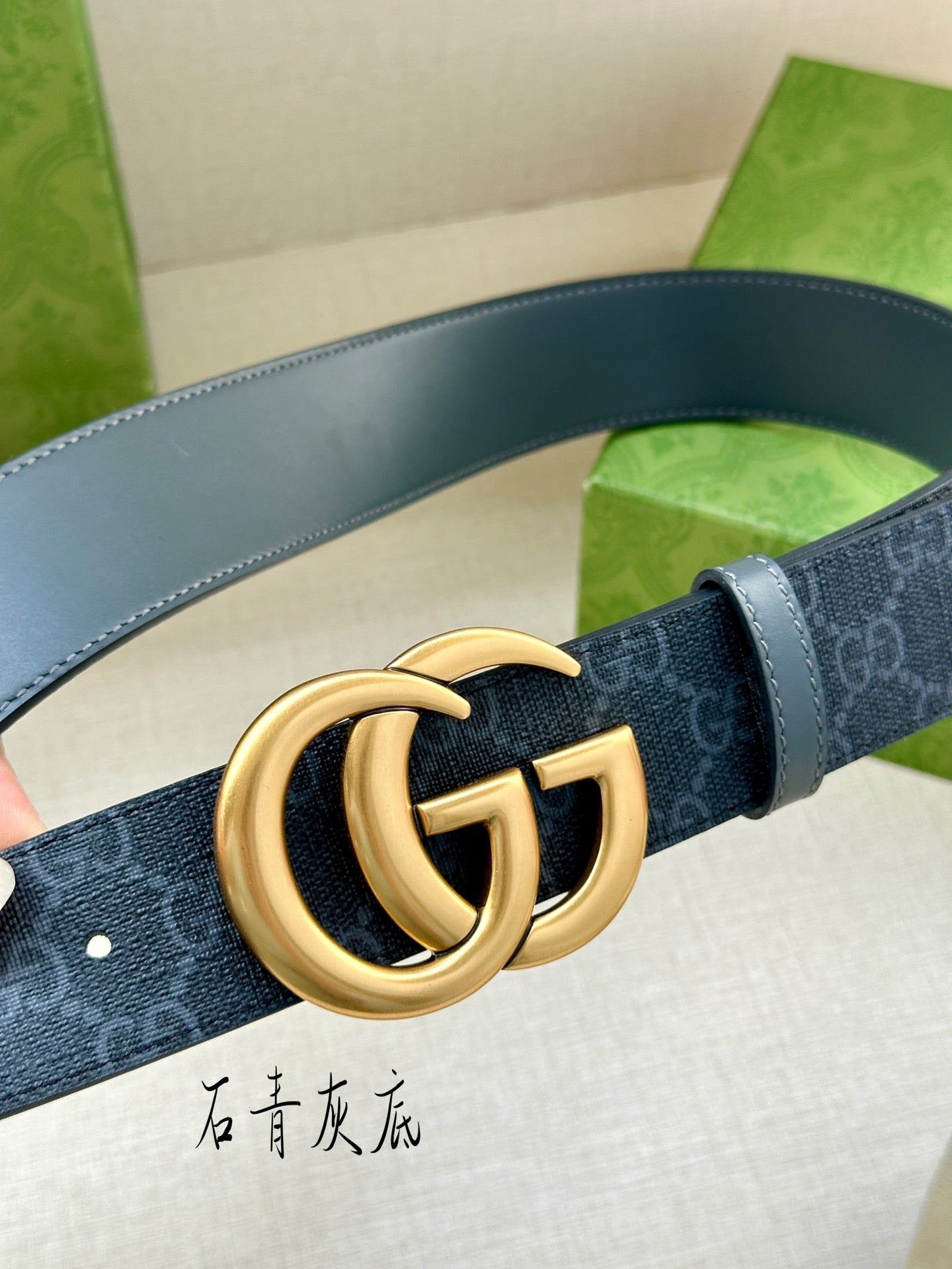 Gucci belt close-up: dark blue monogram strap with gold-tone GG logo buckle