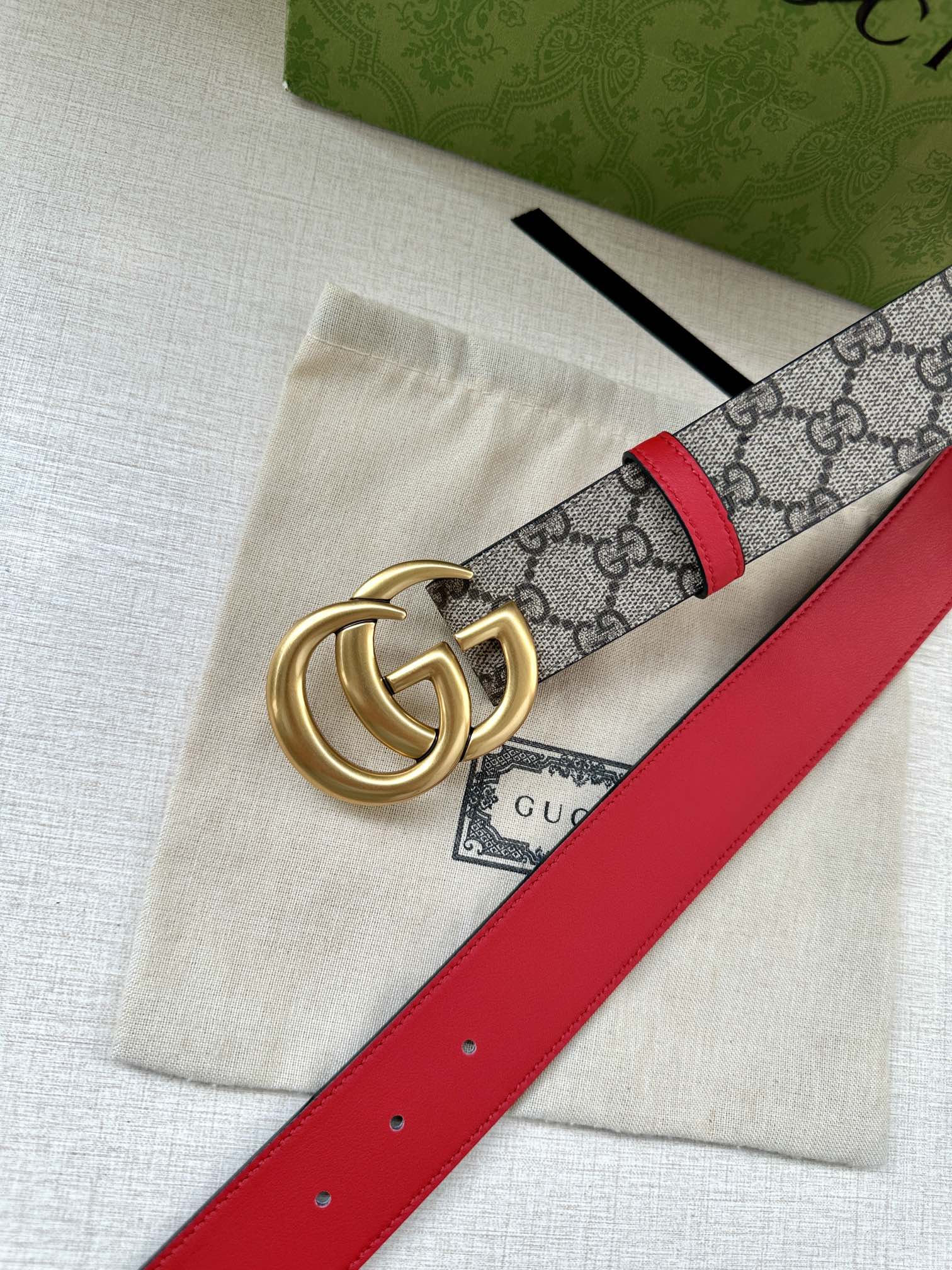 Gucci GG canvas belt with red leather edge and gold double-G buckle, angled