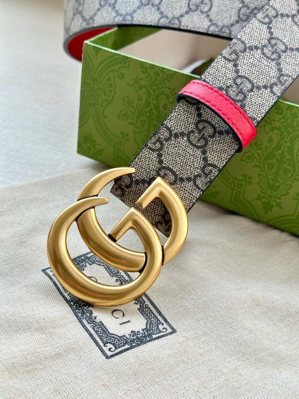Gucci GG canvas belt with red leather edge and gold double-G buckle, close-up