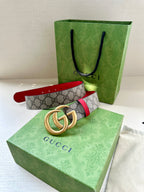 Gucci GG canvas belt with red trim and gold double-G buckle, laid flat
