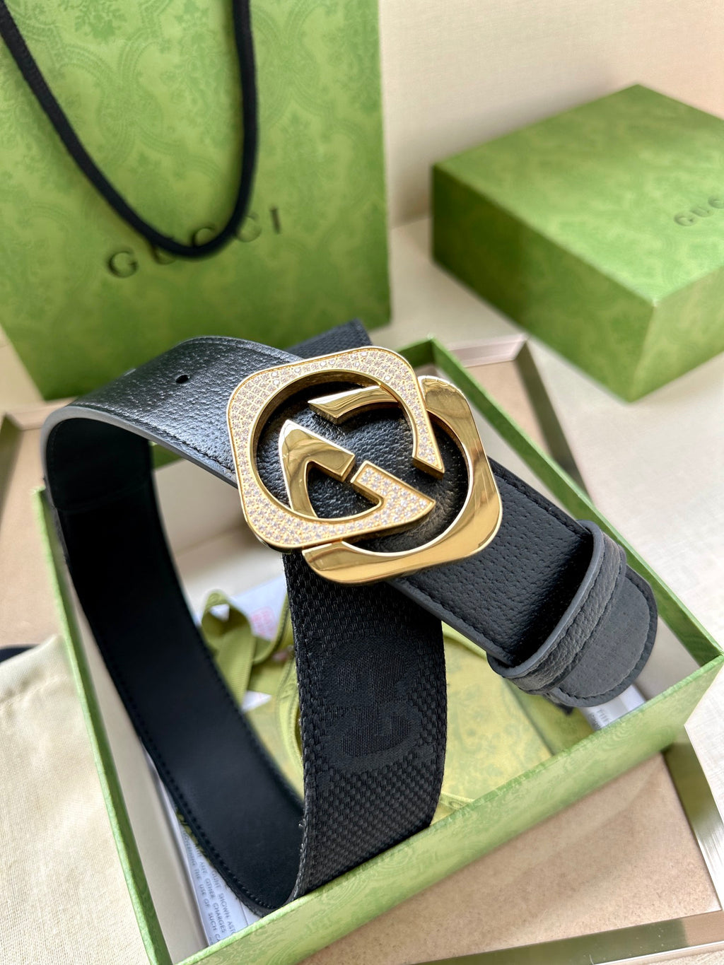 Dark navy leather belt with gold-tone GG logo buckle, close-up on front