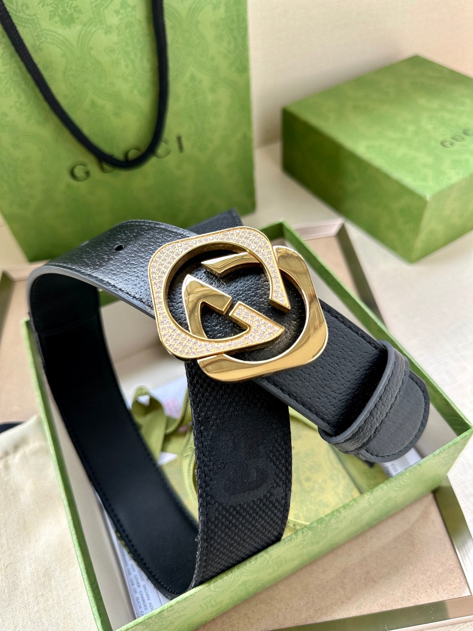Dark navy leather belt with gold-tone GG logo buckle, close-up on front