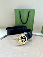 Dark navy leather belt with gold-tone GG logo buckle and perforated strap