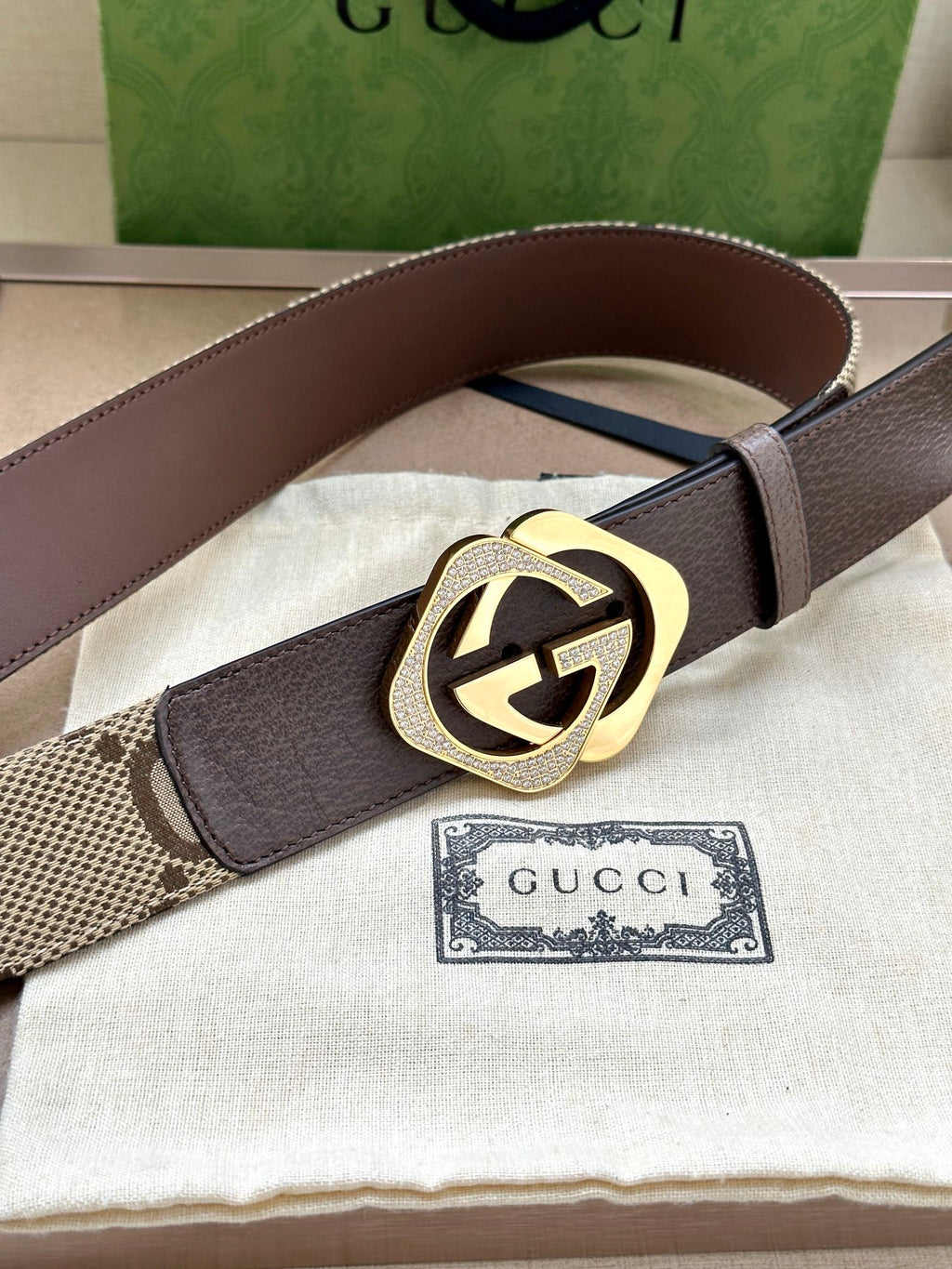 Gucci belt with dark brown leather strap and gold-tone circular GG buckle.