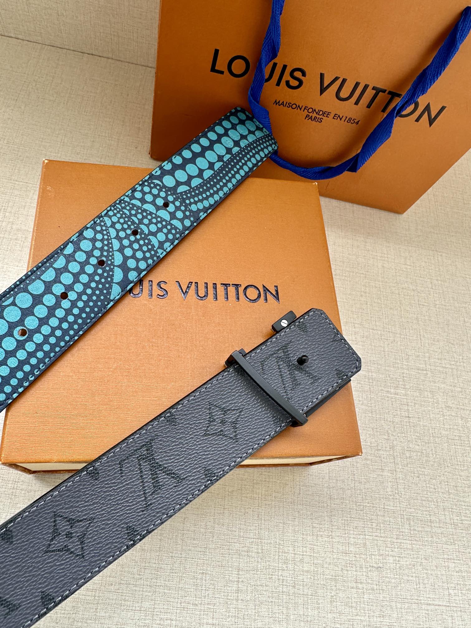 Louis Vuitton belt with turquoise patterned strap and dark gray leather keeper