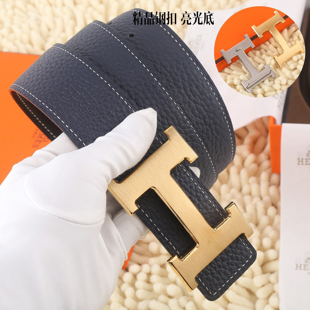 Navy leather belt close-up of gold-toned H buckle with stitched strap edges.