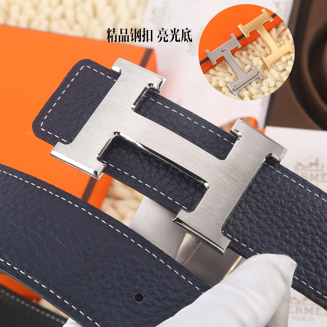 Navy leather belt close-up: large silver-toned H buckle with stitched strap.