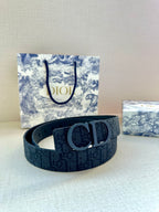 Dark blue designer belt with metal “D” buckle, placed on a box
