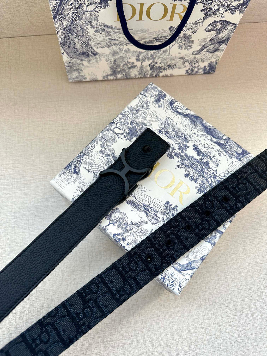 Dark blue fabric belt with repeating logo pattern and large buckle, laid diagonally