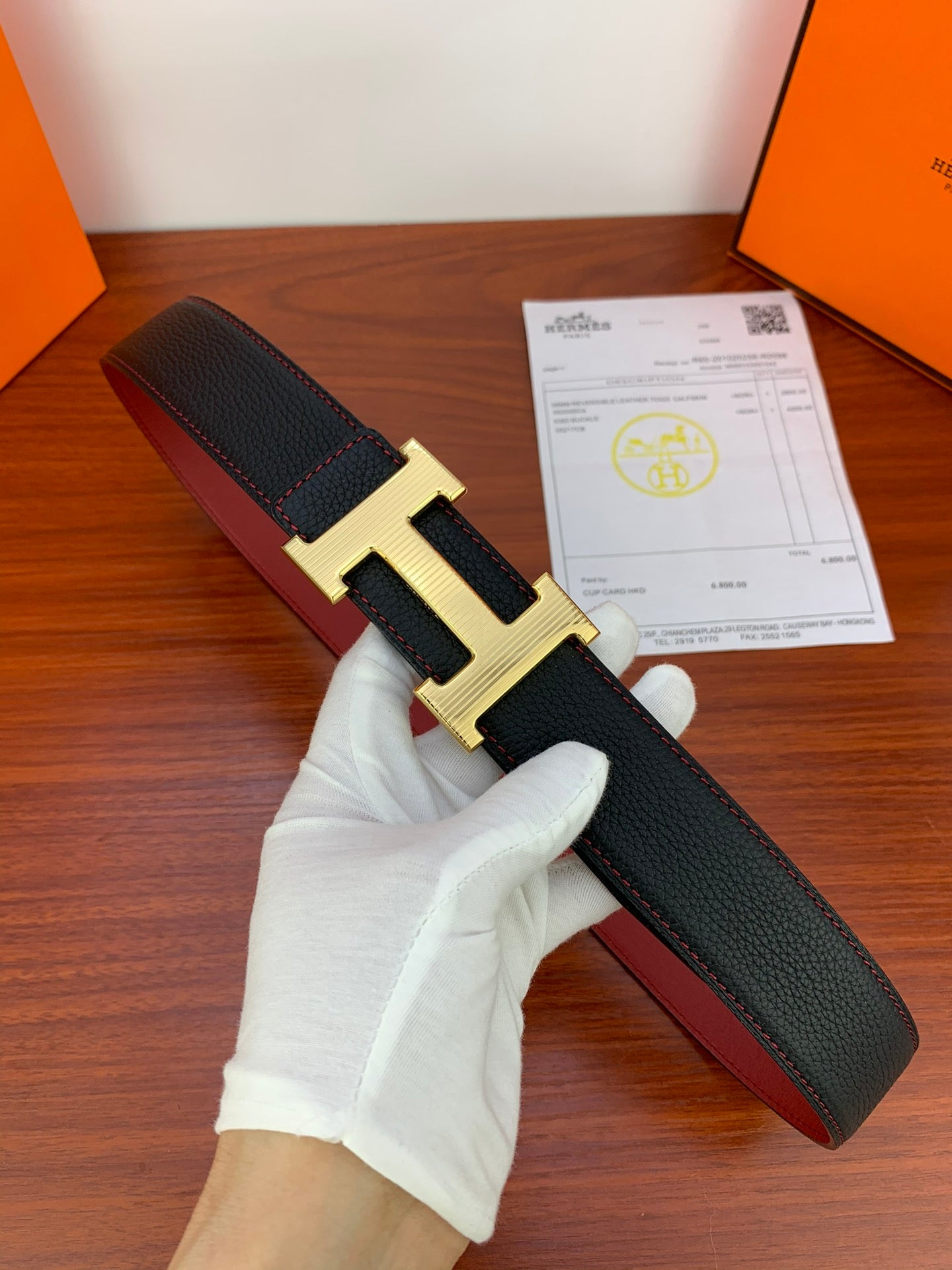 Black leather belt with gold-tone H buckle, shown with end folded upward.