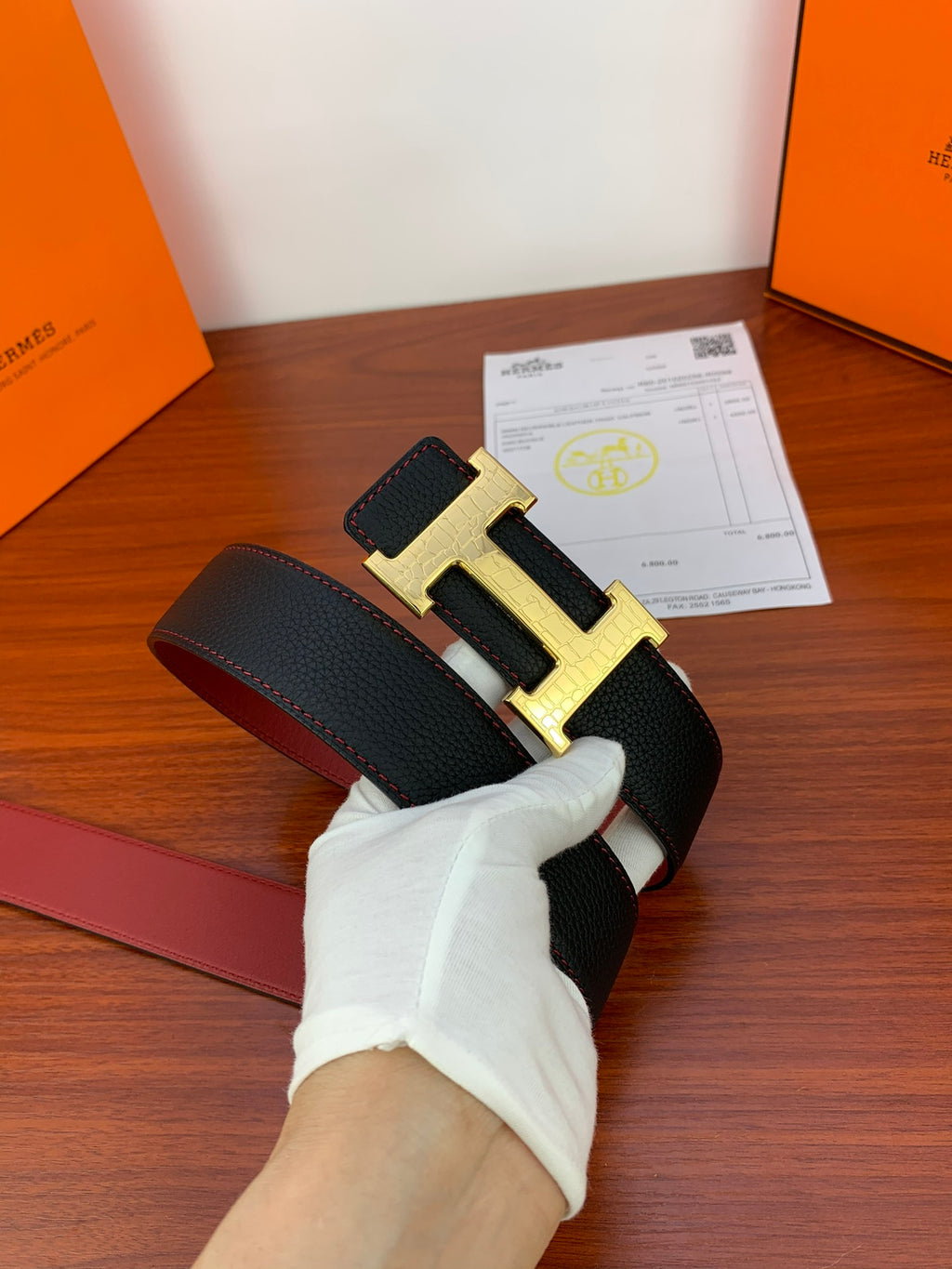 Hermes reversible leather belt, angled view black strap with gold-tone H buckle