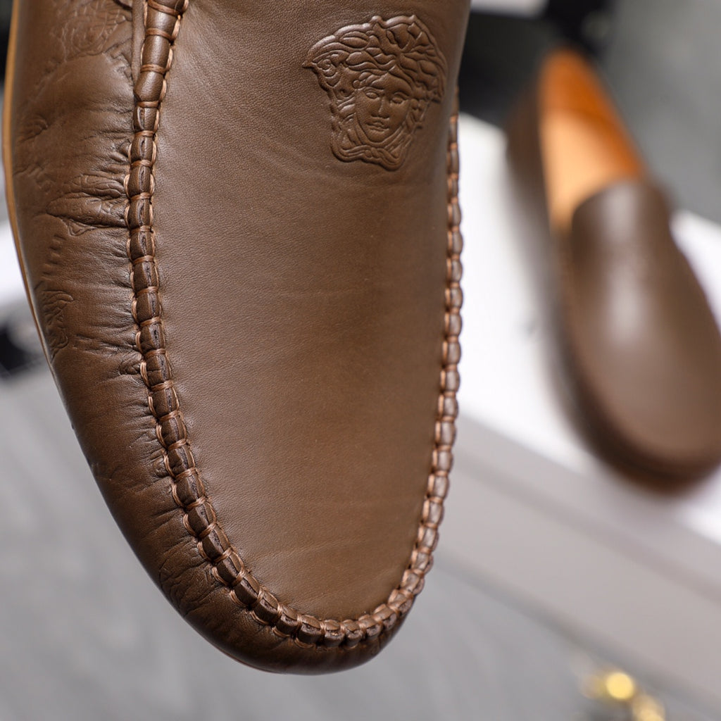 Versace brown leather loafer vamp close-up with embossed face emblem and stitching