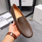 Versace brown leather loafer held in hand, embossed face detail on vamp