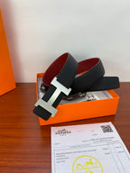 Black leather belt with silver-tone H buckle on orange box and paperwork