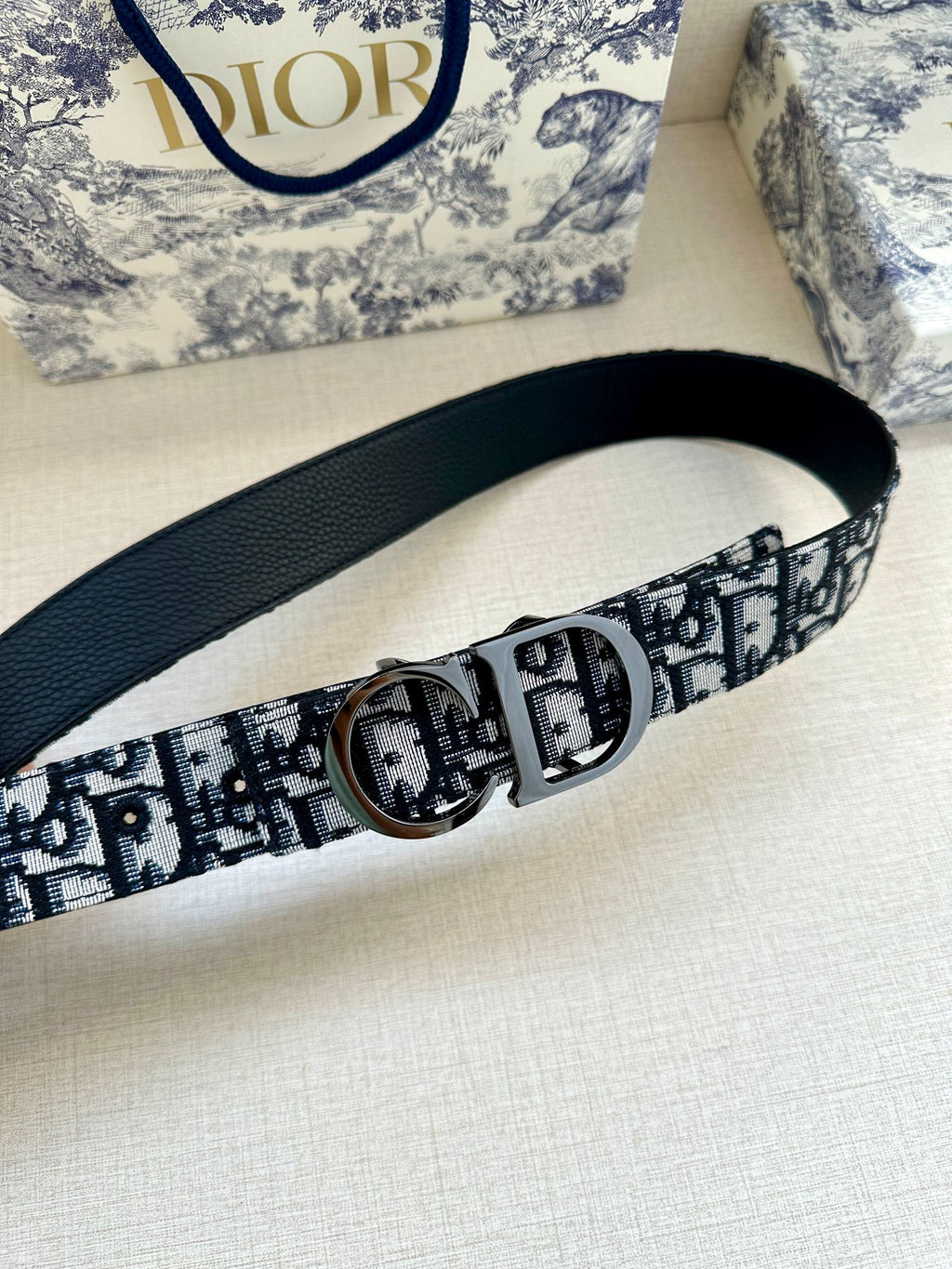 Dior belt with navy leather backing, repeating monogram webbing, and silver round buckle