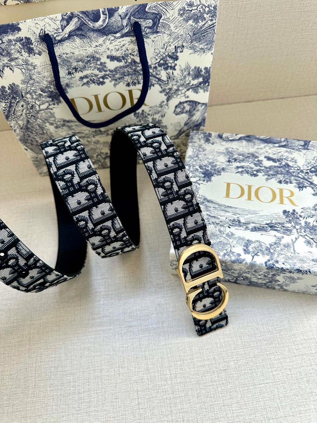 Dior belt and buckle on display: navy-and-white logo jacquard strap, gold CD