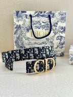 Dior belt laid out, dark navy/black patterned strap with gold double-ring buckle