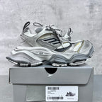 Balenciaga unisex sneakers on box, silver uppers with black logo panels and yellow trim.