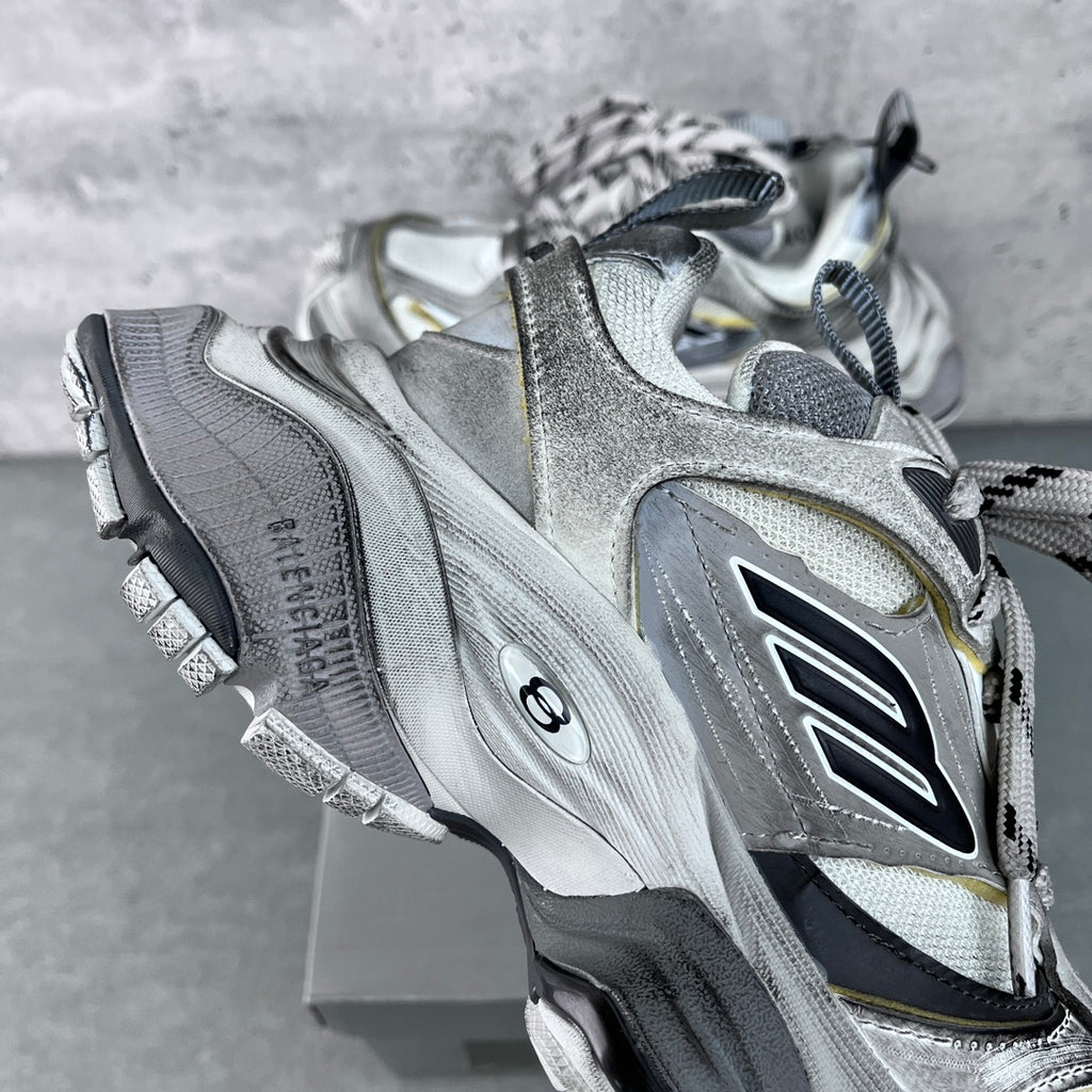 Balenciaga unisex sneakers side view, silver leather-style panels with black logo detail.