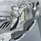Balenciaga unisex sneaker close-up, silver mesh upper with black panel and yellow stripe.
