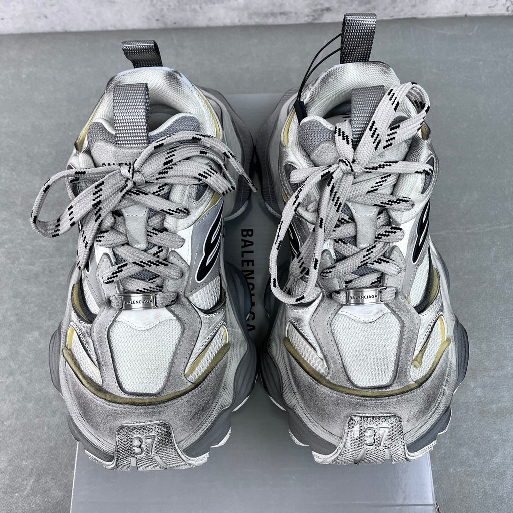 Balenciaga unisex sneakers front view, silver uppers with black logos and neon yellow accents.