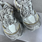 Balenciaga unisex sneakers pair, silver knit uppers with black laces and yellow side piping.
