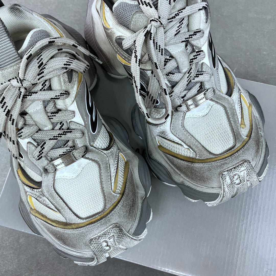Balenciaga unisex sneakers pair, silver knit uppers with black laces and yellow side piping.