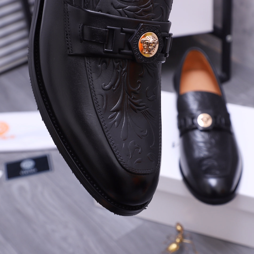 Versace black leather loafer close-up with embossed floral pattern and gold medallion buckle