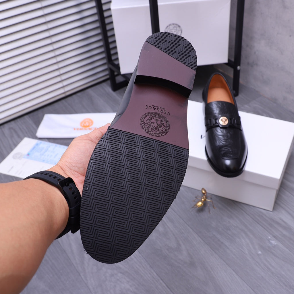 Versace black loafer outsole with geometric tread pattern, held in hand