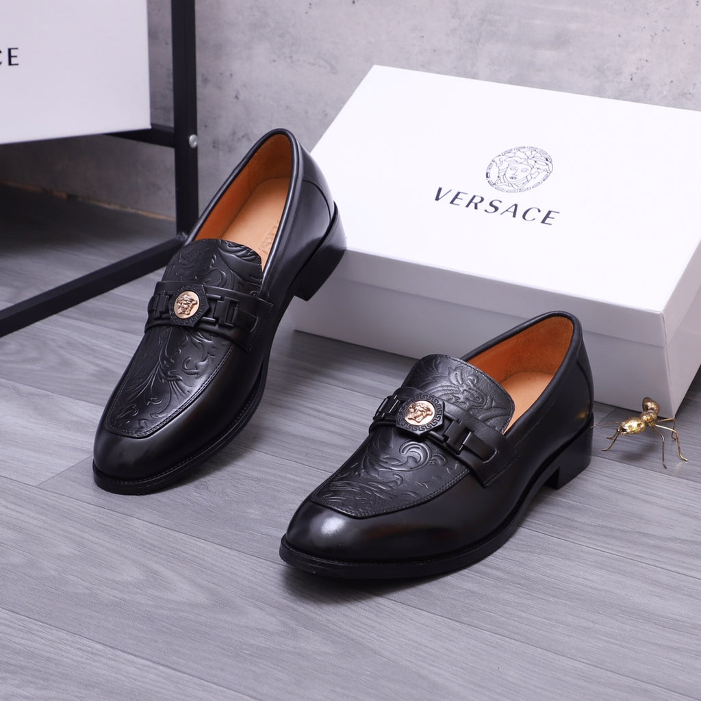 Versace black leather loafers with embossed scrollwork and buckle strap