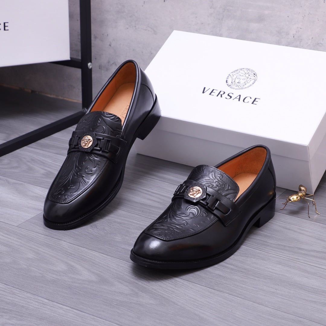 Versace black leather loafers with embossed scrollwork and buckle strap
