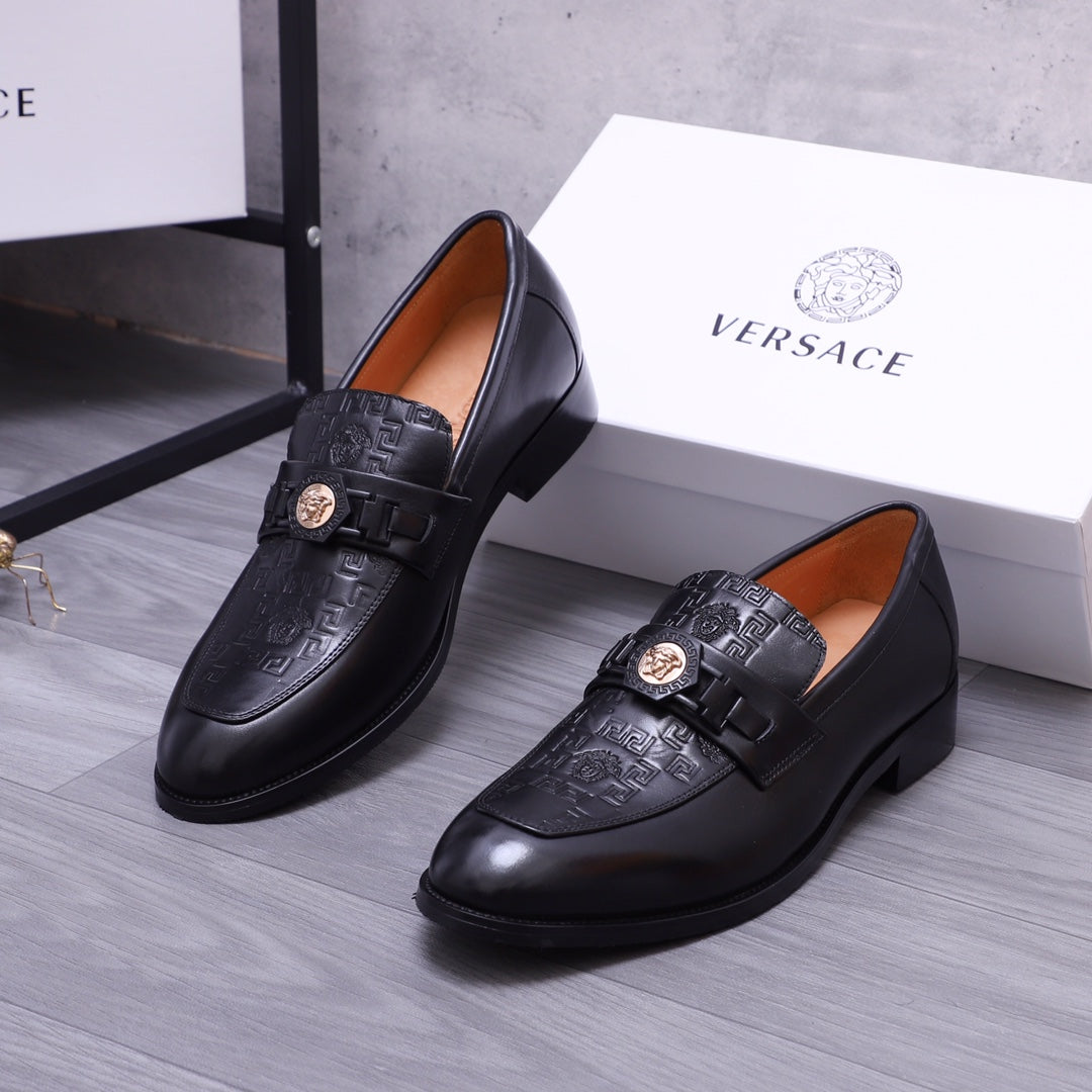 Pair of black Versace loafers with embossed pattern and gold crest, side angle