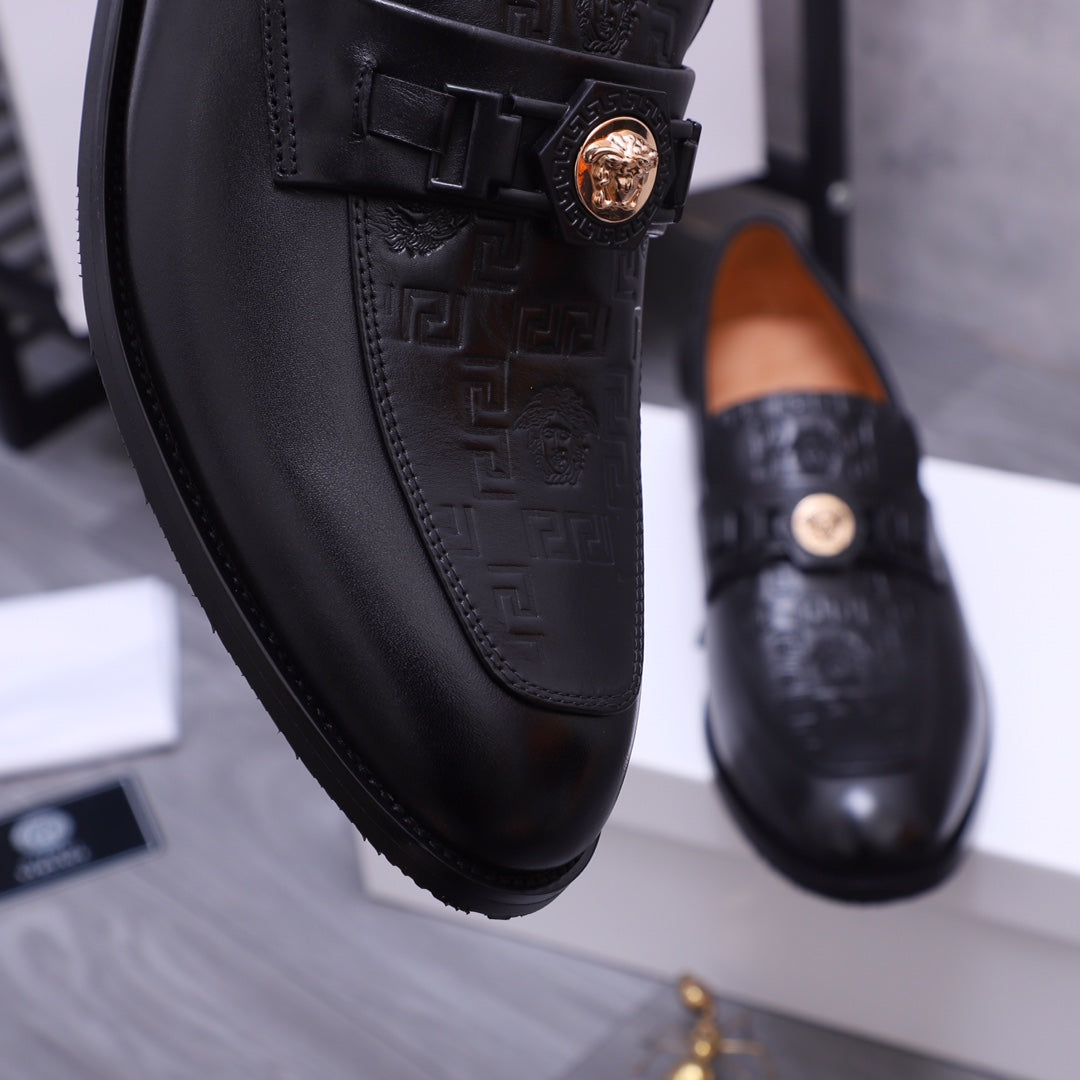 Extreme close-up of black Versace loafer with gold crest buckle and embossed detail